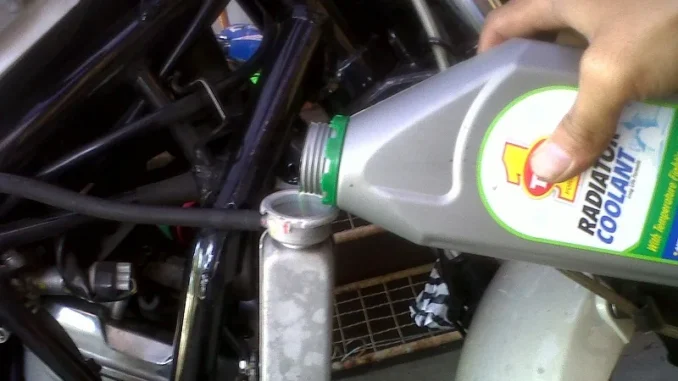 Menuang cairan radiator coolant dari botol ke lubang pengisian radiator motor