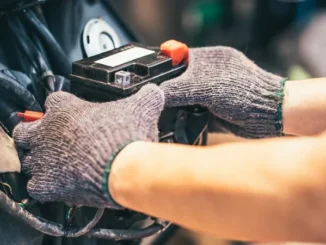 Tangan bersarung tangan melepas aki dari rumah aki sepeda motor