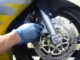Tangan bersarung tangan memegang kaliper rem depan di samping cakram motor sport kuning