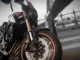 Garpu depan upside down emas Honda CB650R dengan cakram depan dan tulisan ABS di kakinya, berlatar jembatan