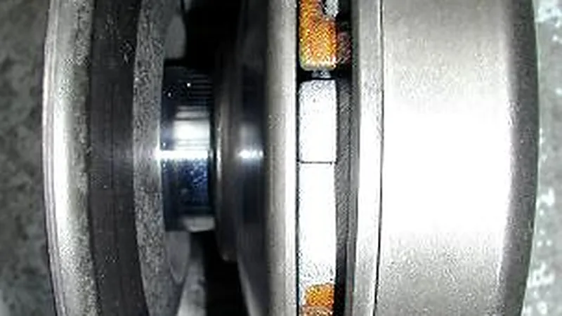 Bagian dalam CVT motor matic dari dekat: puli variator dengan roller pemberat oranye terpasang di antara kedua sisinya