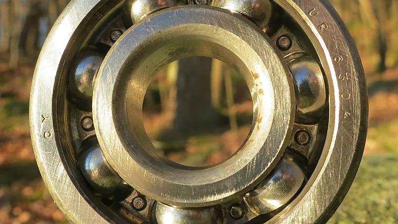 Bearing pelor tipe deep groove dari dekat: bola-bola baja dan alurnya terlihat jelas, jenis laher yang sama dengan yang bekerja di komstir