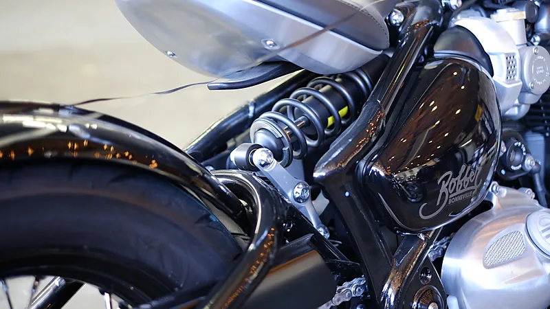 Shockbreaker belakang motor dengan per spiral terlihat jelas, terpasang di rangka Triumph Bonneville Bobber hitam mengilap