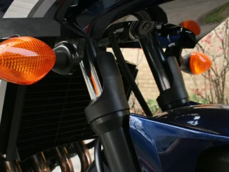 Sepasang lampu sein depan bermika oranye pada motor sport biru tua