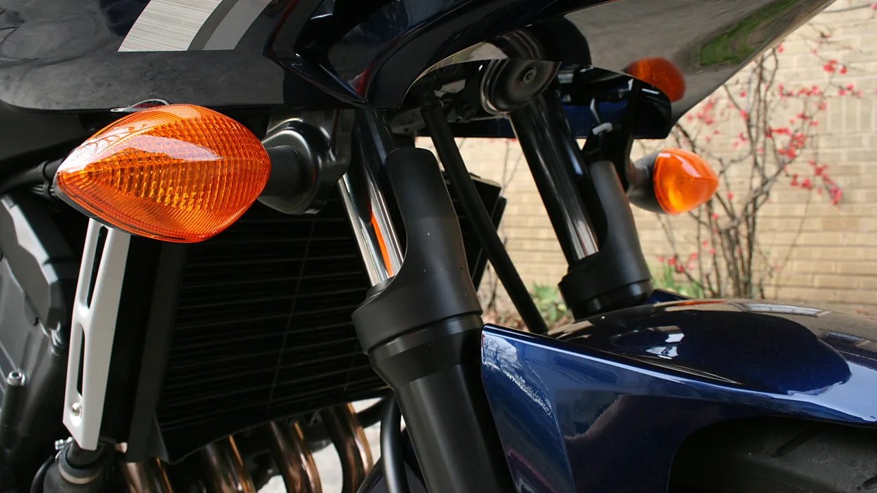 Sepasang lampu sein depan bermika oranye pada motor sport biru tua