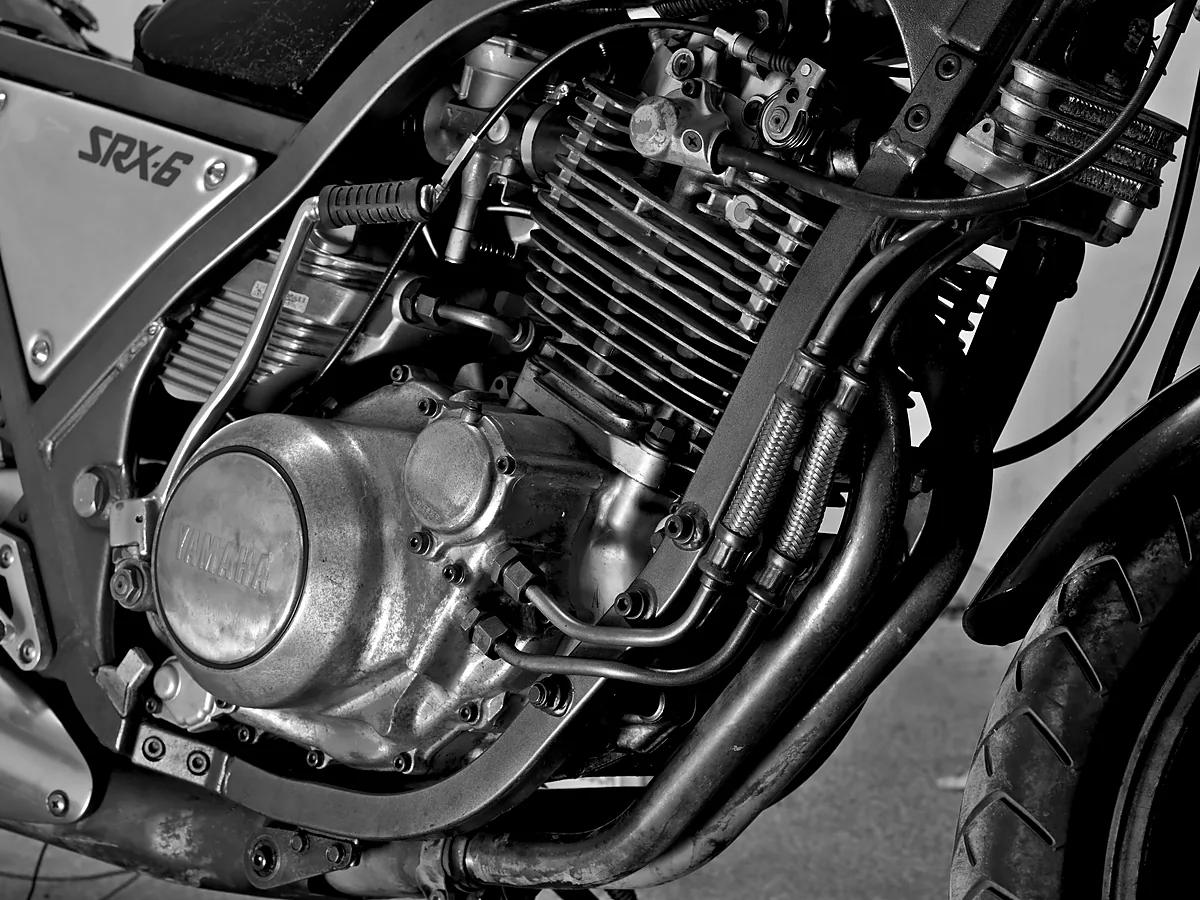 Mesin satu silinder besar Yamaha SRX-6 berpendingin udara dengan sirip silinder tebal dan bak mesin berlogo Yamaha, foto hitam putih