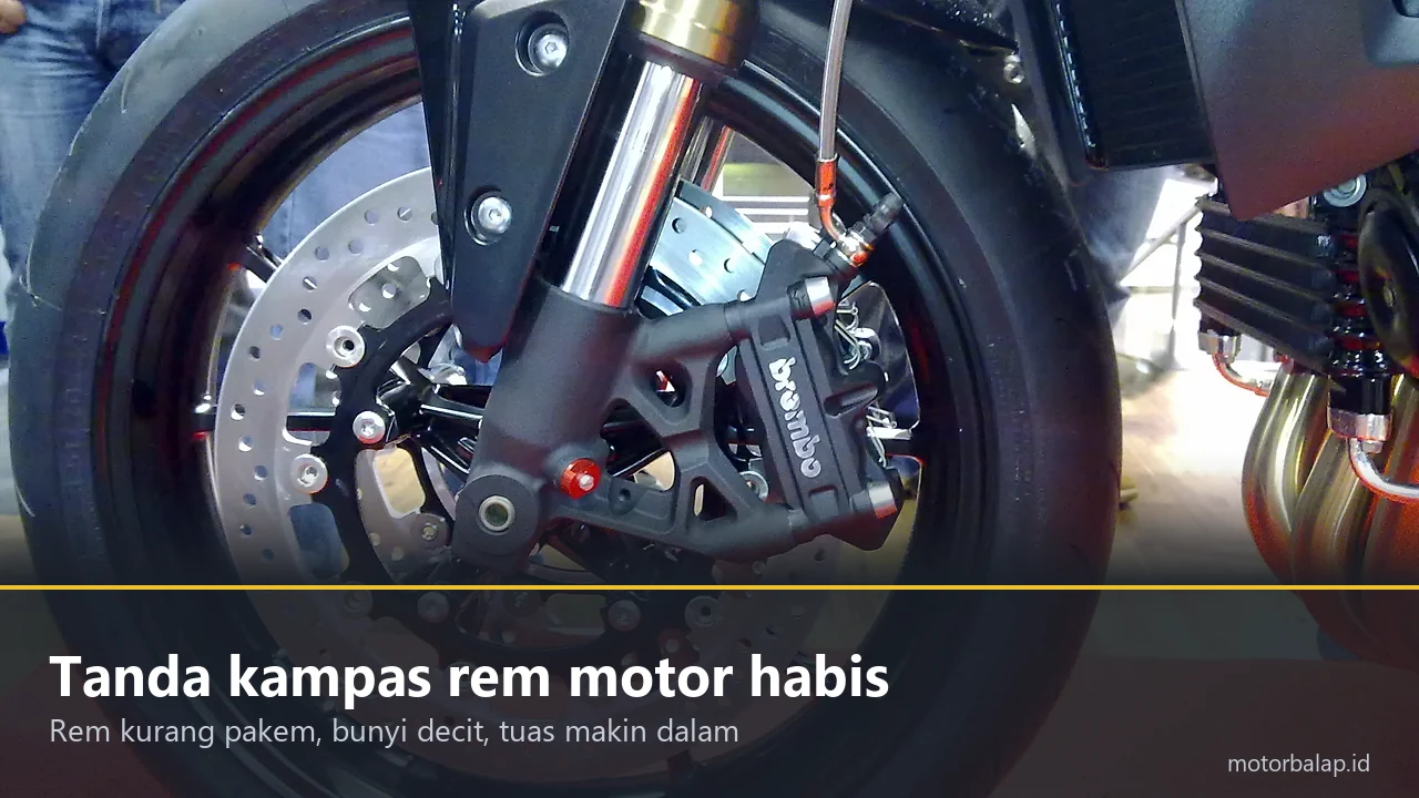 Kaliper rem Brembo dan cakram berlubang pada roda depan motor Triumph Speed Triple, berpita judul Tanda kampas rem motor habis